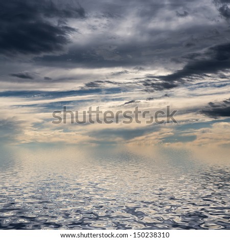 Sky with dark clouds reflected in water surface.