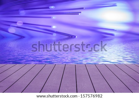Violet fiber optic reflected in water surface. View from wooden pier.