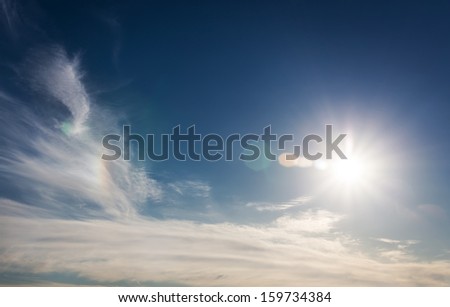 Blue sky with sun and clouds. With lens flare effect.