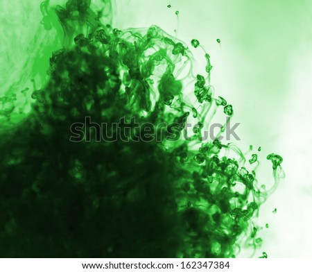 Green watercolor in water with small pieces of paint.
