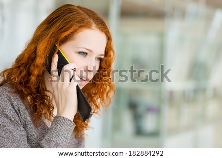 Redhead girl speaking by phone. Selective focus with shallow depth of field.