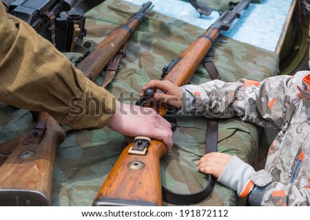 VLADIVOSTOK, RUSSIA - MAY 9, 2014: Children inspect weapons since World War II during festivities devoted to Victory Day.