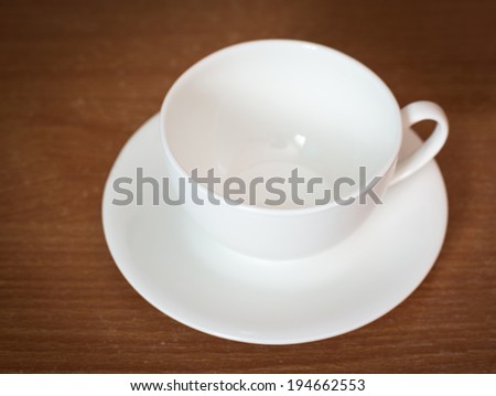 Empty coffee cup on old wooden table. Selective focus on edge of cup.