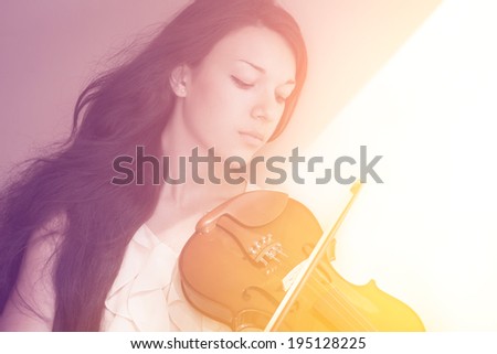Portrait of a young female playing the violin. With sunshine. Color toned image.