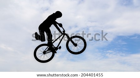 Silhouette of a man doing an jump with a bmx bike.