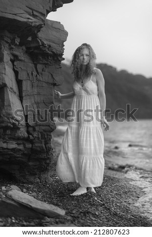 Beautiful young woman goes along the coast. Black and white image.
