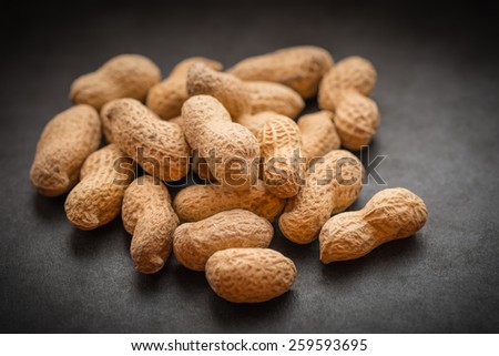 Natural looking roasted peanuts on a dark background.