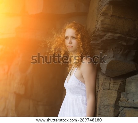Portrait of redhead woman in a white dress with sunshine effect.