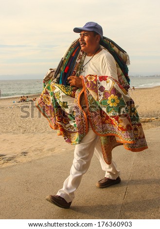 PUERTO VALLARTA, MEXICO - FEBRUARY 7:  Mexican Street vendor sells table cloths and blankets on February 7, 2014 on the waterfront, Malecon, in Puerto Vallarta, Mexico