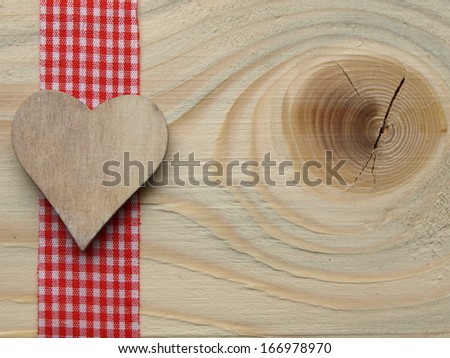 wooden background with a red checked ribbon and a heart