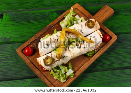 Grilled enchiladas with meat, vegetables and jalapeno pepper on wood board