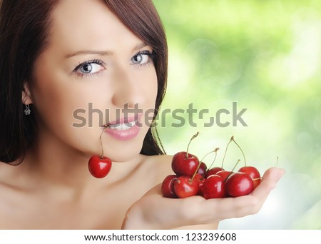Beautiful woman with cherry fruits on fresh green background