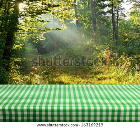 Empty gingham table with forest background. Ready for product display montage.