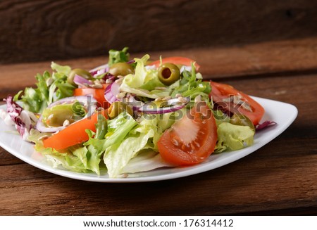 Salad with tomatoes and olives on wooden background