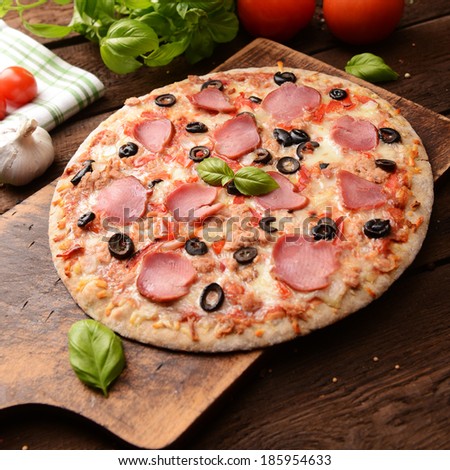 Homemade pizza with black olives, tuna and italian ham