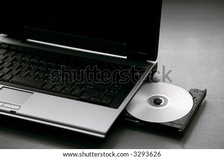 A laptop with the DVD drive open and disc inserted