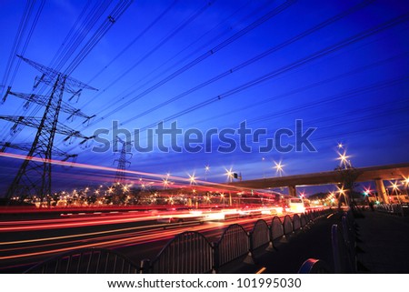 View long exposure of cars passing through  of the highway and transmission tower