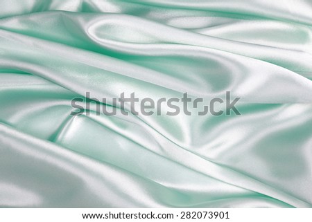 Light green Silk cloth of abstract backgrounds or wavy folds or satiny silk texture satin velvet material or elegant wallpaper design curve.