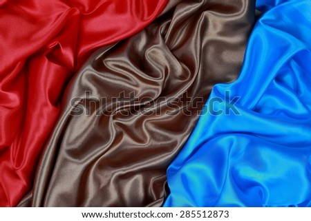 Brown and red and blue Silk cloth of abstract backgrounds or wavy folds or satiny silk texture satin velvet material or elegant wallpaper design curve