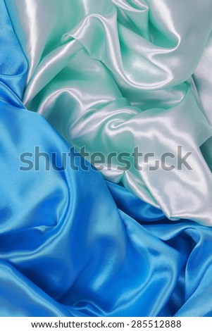 Blue and light green Silk cloth of abstract backgrounds or wavy folds or satiny silk texture satin velvet material or elegant wallpaper design curve
