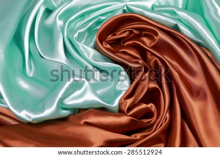 Brown and light green Silk cloth of abstract backgrounds or wavy folds or satiny silk texture satin velvet material or elegant wallpaper design curve