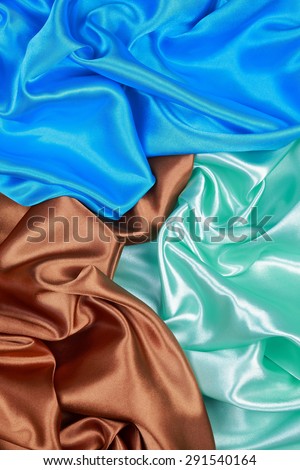 Brown and light green and blue Silk cloth of abstract backgrounds or wavy folds or satiny silk texture satin velvet material or elegant wallpaper design curve