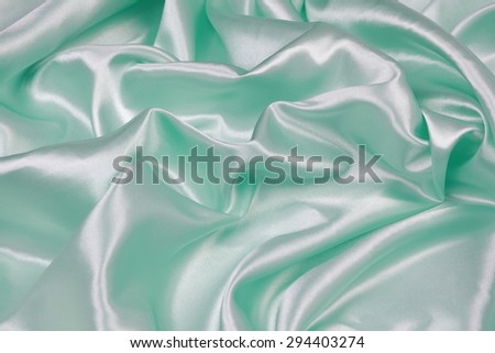 Light green Silk cloth of abstract background or wavy folds or satiny silk texture satin velvet material or elegant wallpaper design curve.