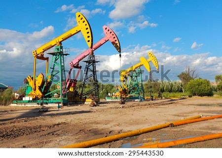 Under sunny golden yellow and pink Oil pump oil rig energy industrial machine for petroleum crude of countryside,dirt road