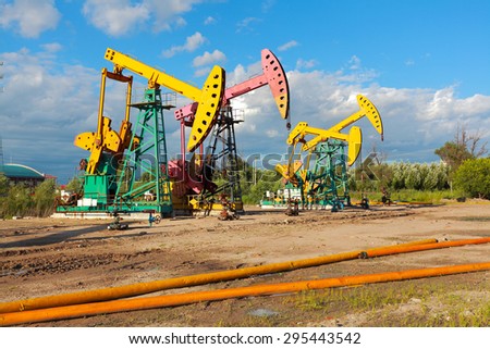 Under sunny golden yellow and pink Oil pump oil rig energy industrial machine for petroleum crude of countryside,dirt road