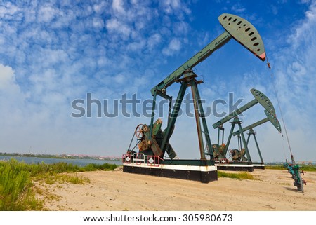 Green Oil pump oil rig energy industrial machine for petroleum crude on the side of dirt road
