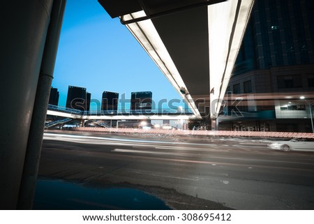 Intersection of urban footbridge and highway auto with light trails of night scene