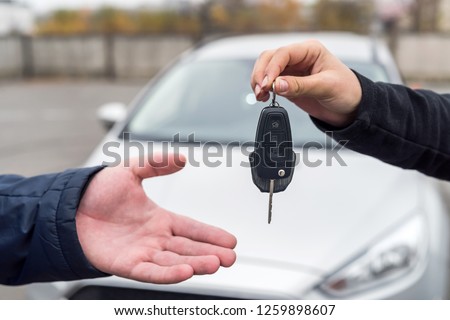 Female hand giving and male hand receiving car keys