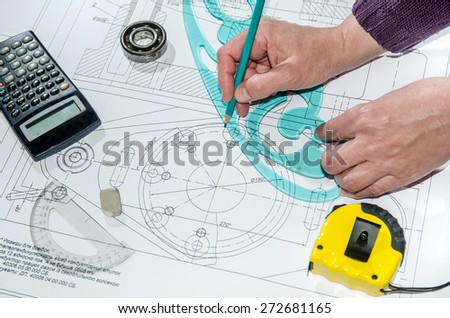 engineering drawings with human hands drawing a project by pencil on paper