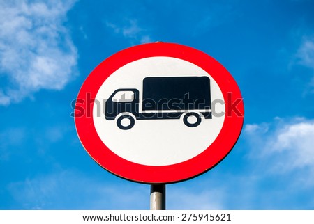 Round speed limit trucks road sign above blue cloudy sky
