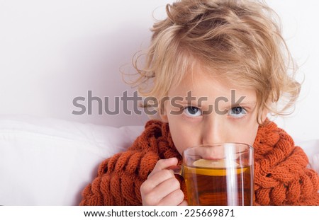 Cute blond girl lying in bed with cup of tea