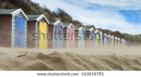 Beach Huts in Sand Storm at Saunton Sands, Devon, UK.