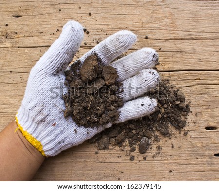 white garden  gloves a with soil  on old wooden background