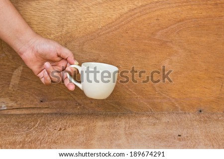 hand give your mug on a wooden floor.