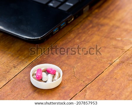 capsule and notebooks on wood table.The concept of hard work and had to take medicine.