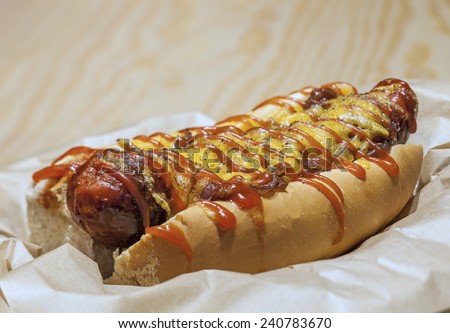 Hot dog with mustard, ketchup, cheddar cheese on table