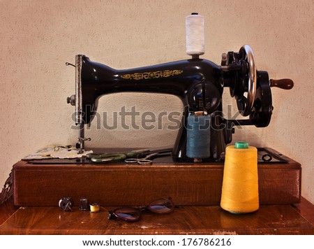 Old sewing machine with scissors and glasses. Sewing machine with manual transmission. Retro concept
