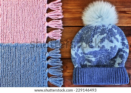 Beautiful knitted scarf and hat with fur pompon on a wooden texture