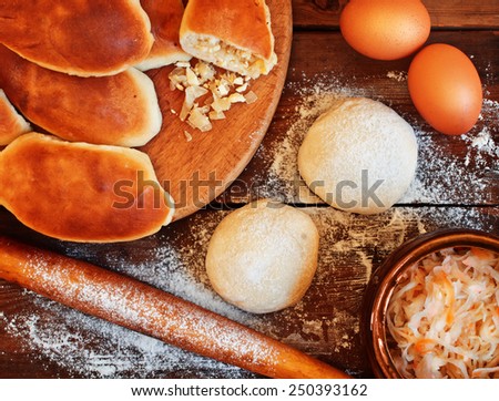 Traditional pies with cabbage and eggs. Dough, rolling pin and pastry on a wooden table