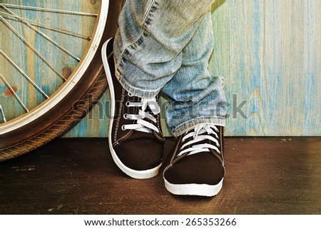 feet in jeans and sneakers alongside a bicycle