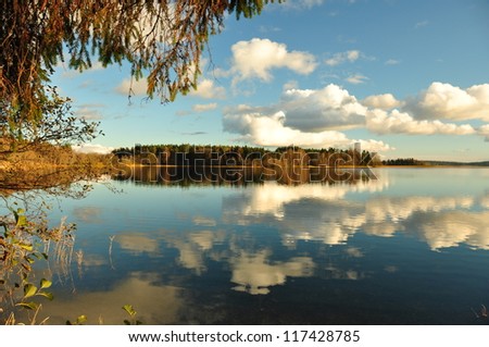 The quiet lake in sunny autumn day. Reflection of clouds on lake waters