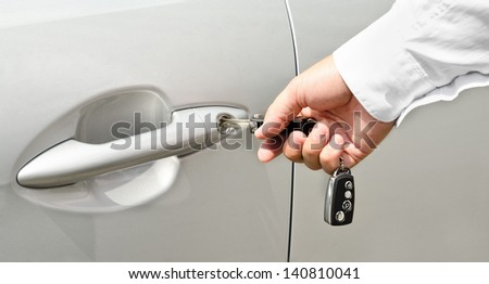 Male hand with key opening car door outdoors