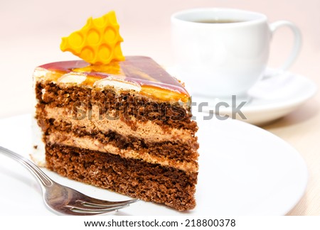 Piece of honey cake on plate with fork and tea cup