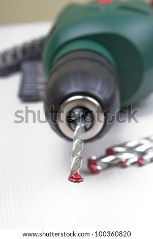 Green electric drill on wooden background