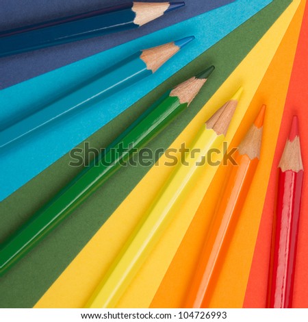 rainbow background of differently colored papers and pencils