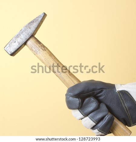 The hand in  worker glove holding the hammer